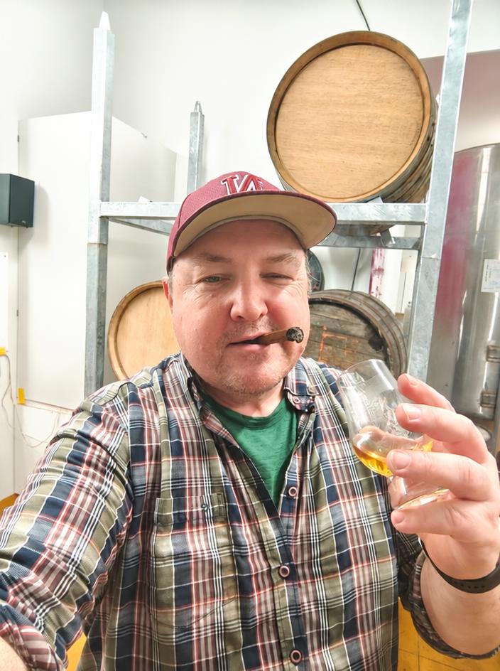 The distiller with a glass of whiskey in the rack room